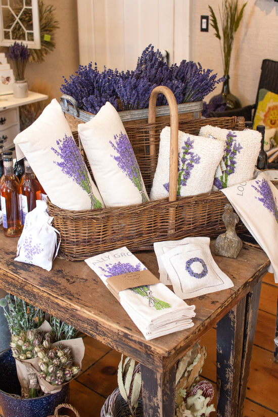 There are lavender products, such as pillow decor, sachets, bundles, and tea towels, displayed freely or in a basket inside the shop.