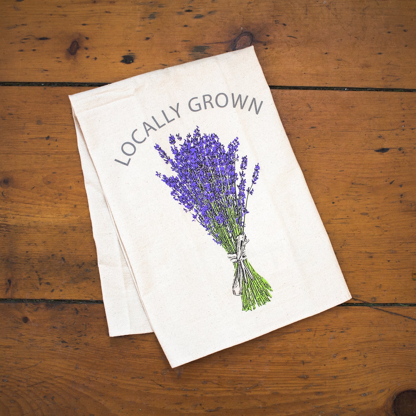 "Locally Grown" Lavender printed tea towel on rustic wooden backdrop.