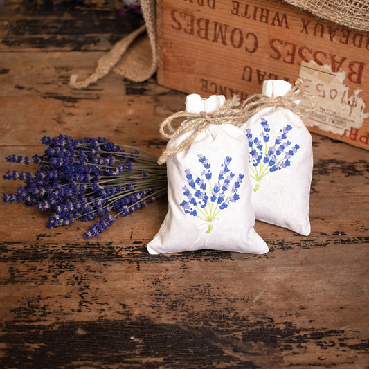Lavender sachet with lavender embroidery and twine ribbon. Sitting next to lavender bundle with rustic wooden background.