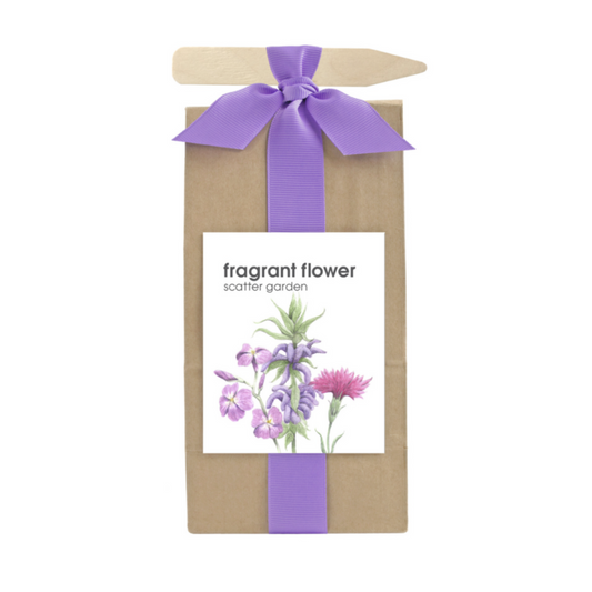 A long brown bag filled with scatter garden seeds. Wrapped with a purple ribbon that also holds a garden marking stick. Label on the front has flower graphics with text that reads "Fragrant Flower Scatter Garden".