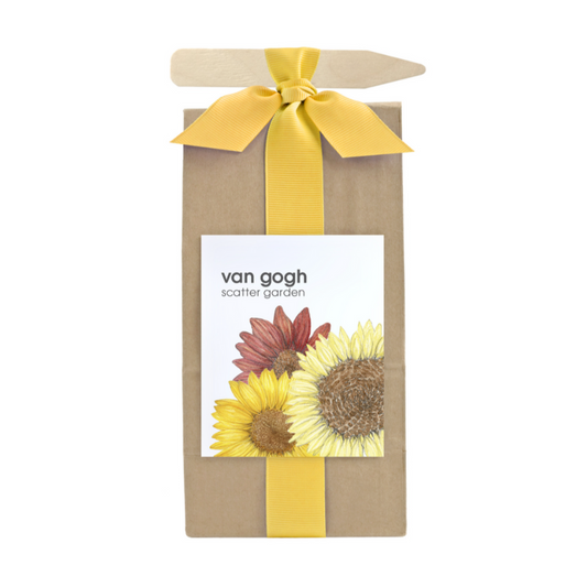 A long brown bag filled with scatter garden seeds. Wrapped with a yellow ribbon that also holds a garden marking stick. Label on the front has a sunflower graphic with text that reads "Van Gogh Scatter Garden".