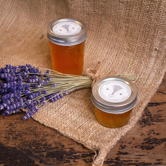 Lavender honey glass jars in 4oz & 8oz sizes, next to lavender bundle on burlap.